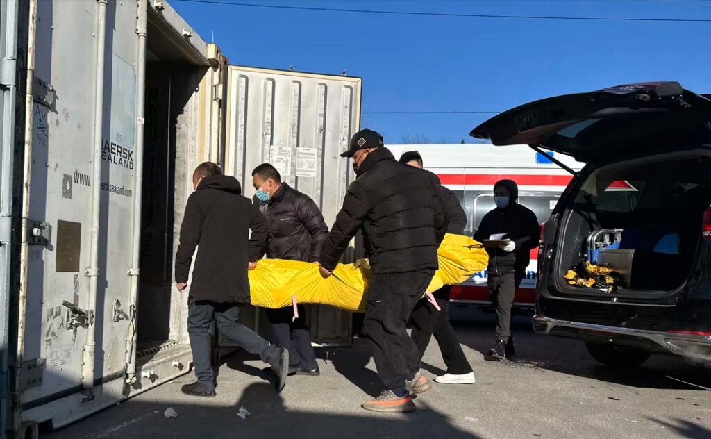 Workers transfer a body into a container for storage Saturday at a crematorium in Beijing.Ng Han Guan AP